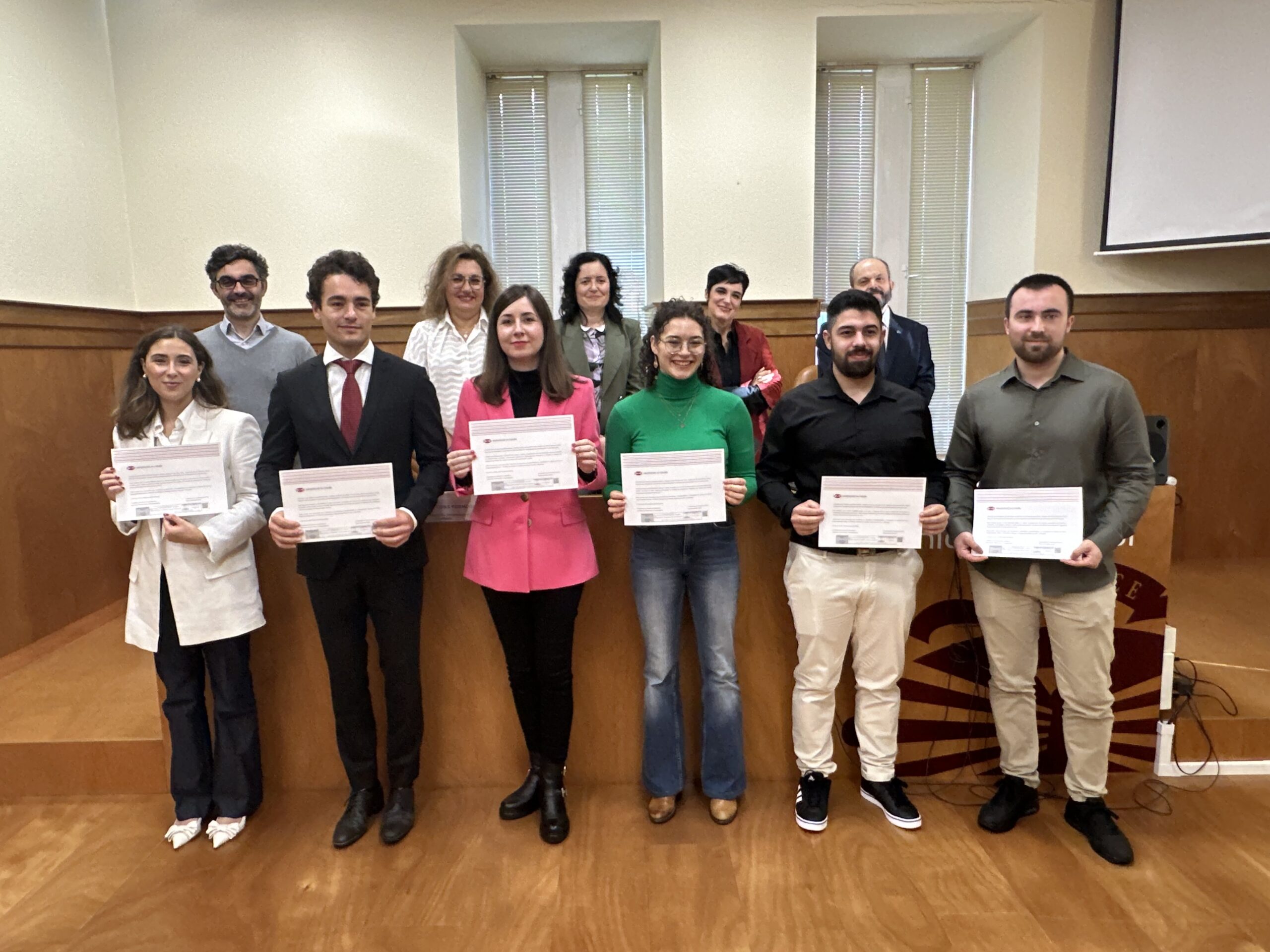 Cinco dos mozos e mozas galardoados acompañados, en segunda fila, polo director do Campus Industrial da Universidade da Coruña, Marcos Míguez, a concelleira de Educación, Universidade e Política Lingüística, Patricia Cons; a vicerreitora do Campus de Ferrol e Responsabilidade Social, Ana Ares; a vicerreitora de Estudantantes e Empregabilidade, María José Lombardía, e o presidente da delegación coruñesa da Asociación de Séniors Españois para a Cooperación Técnica (SECOT), Gonzalo Arias.
